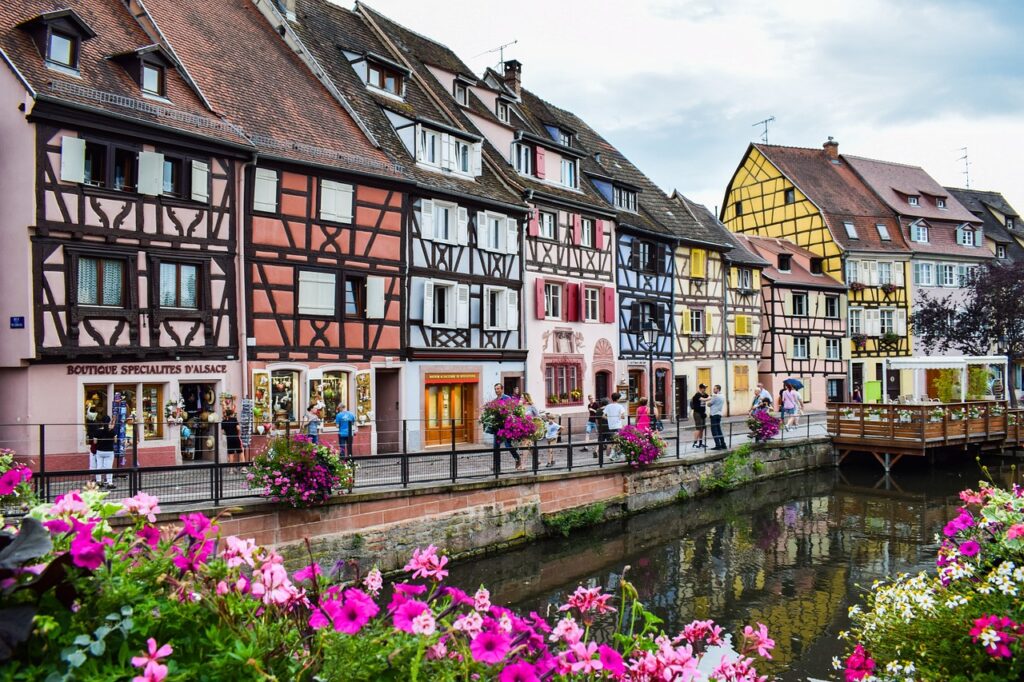 Paisaje en Colmar.
Edificios bajos de dos plantas estilo medieval con colores pastel, al lado del rio. Con flores de tonos blancos y rosas dando a la estampa una bonita y refrescante imagen. 