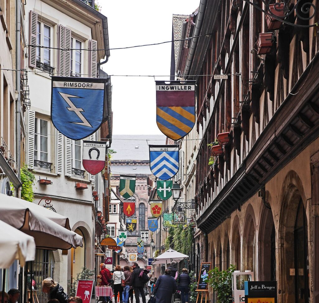  La Petite France, calle estrella llena de paseantes.Con estandartes colgando de  las paredes